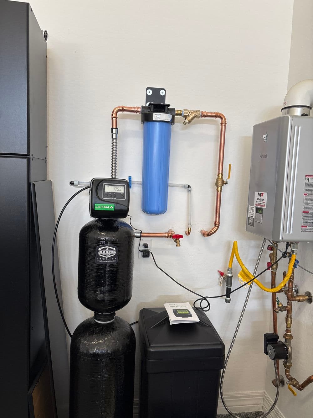 Water filtration system with blue filter, black tank, and connected plumbing setup.