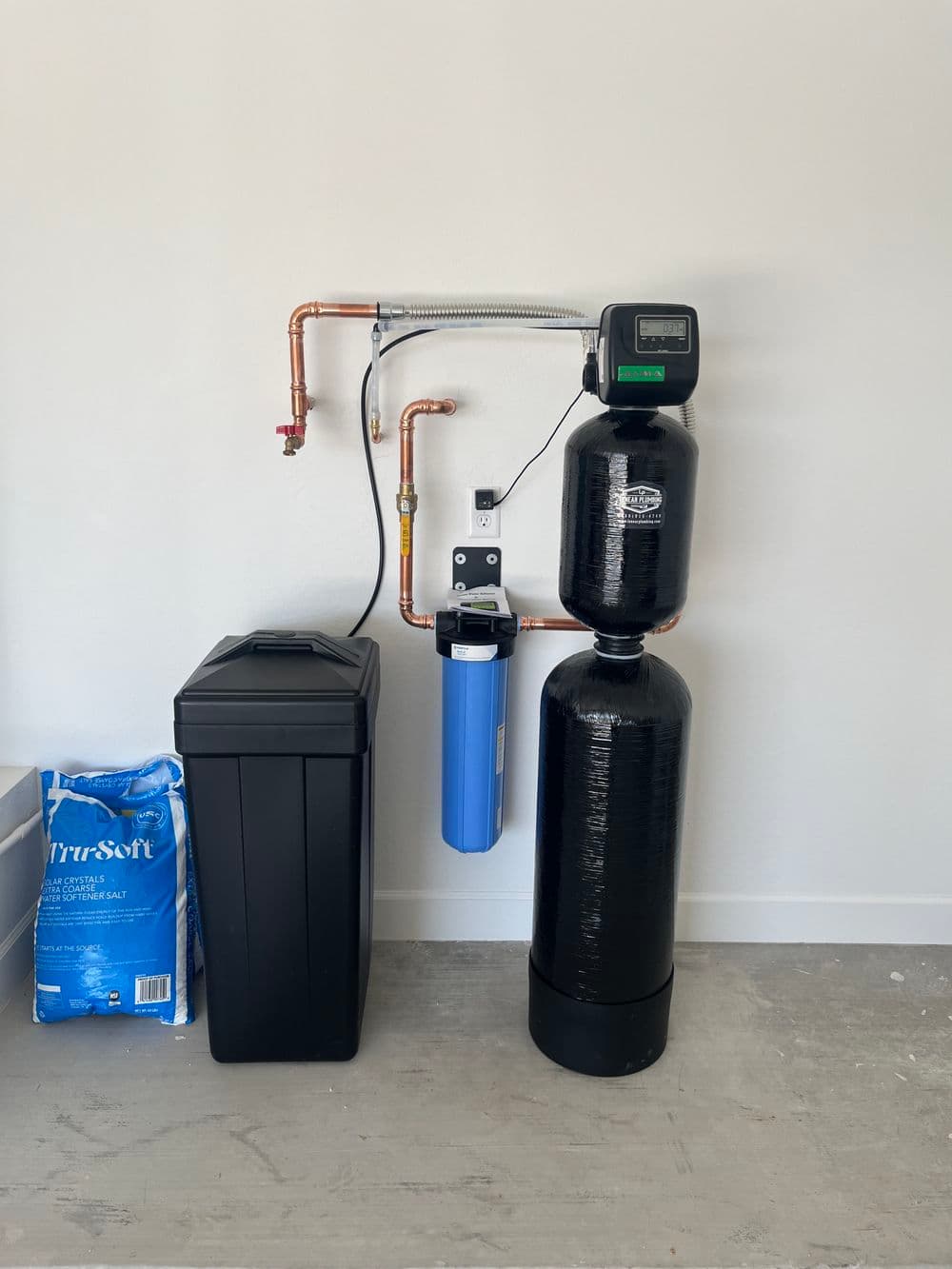 Water filtration system with tank, control panel, and blue filter connected by copper pipes.