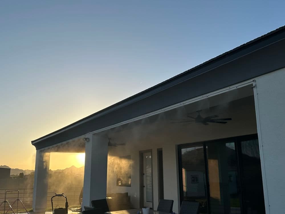Sunset view from a modern patio with mist cooling system and mountain backdrop.