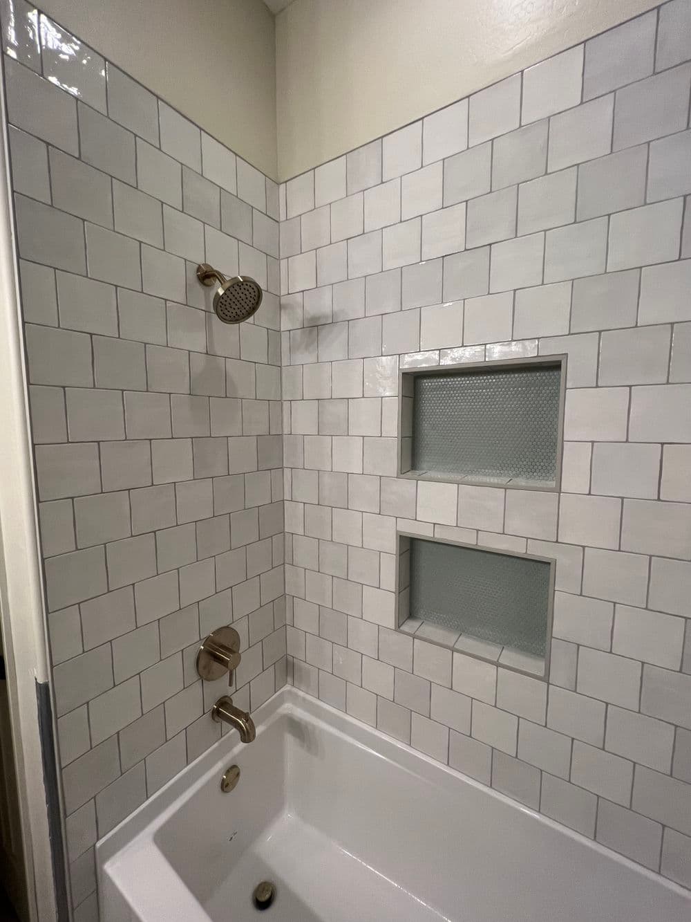 Modern bathroom featuring a white subway tile shower with a sleek showerhead and built-in niches.