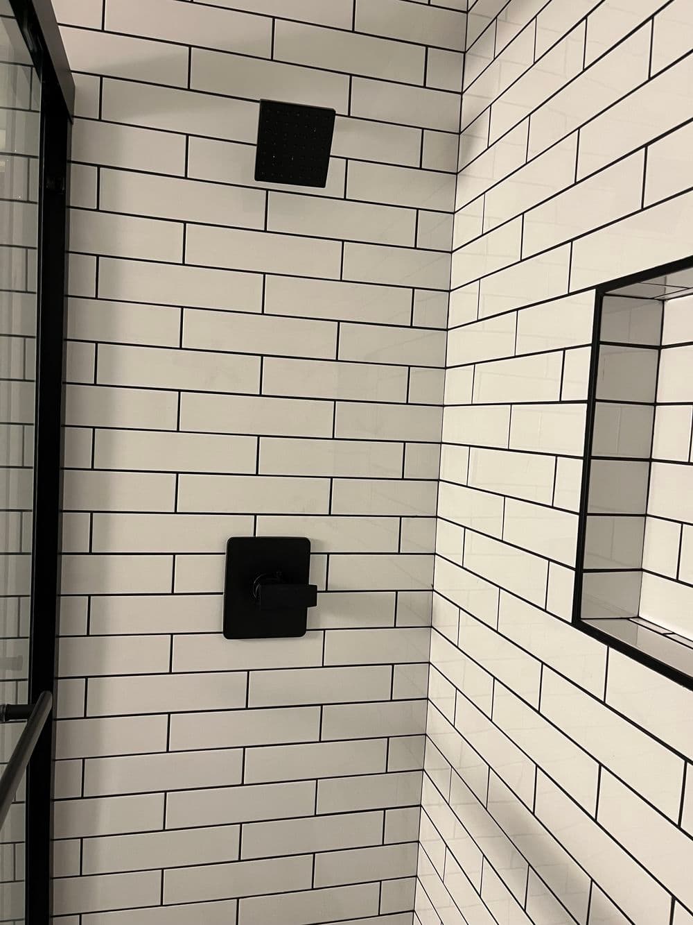 Modern bathroom with black fixtures and white subway tile accents on walls and shower.