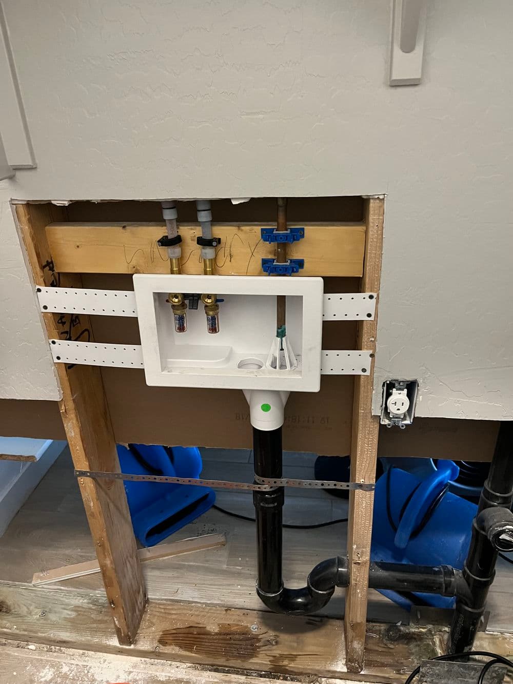 Plumbing installation with pipes, wall framing, and drainage system in a remodel project.